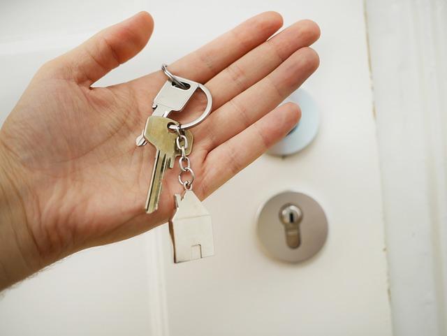 Hand holding keys in front of white door